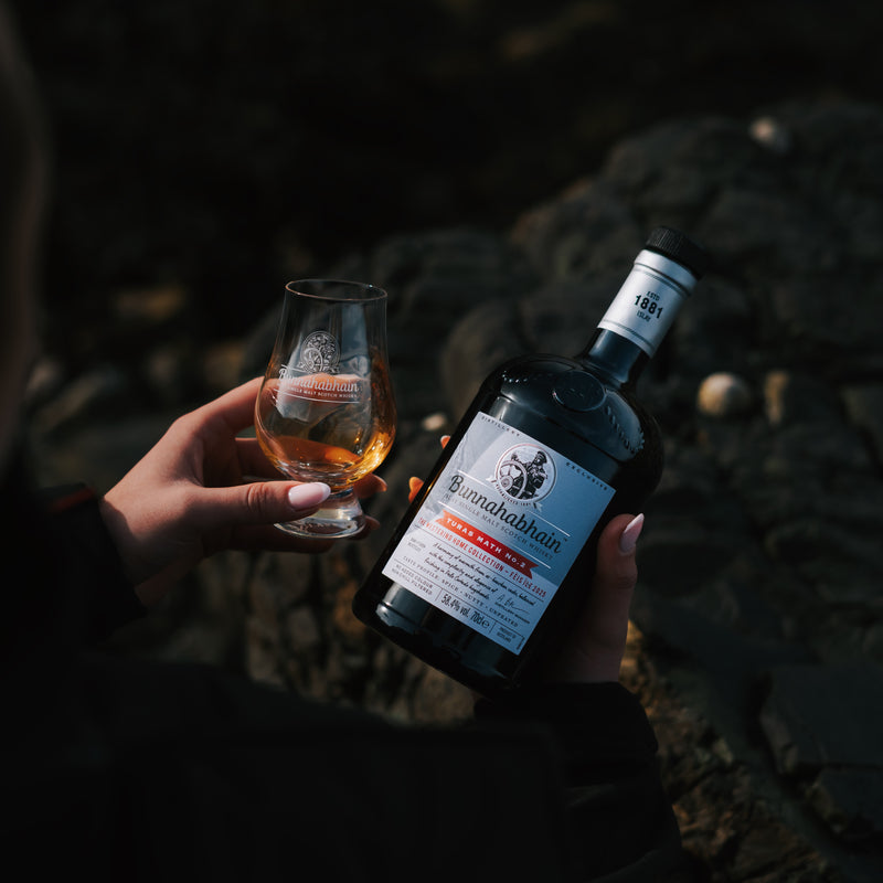 Someone holding Bunnahabhain Turas Math No.2 with a dram in opposite hand