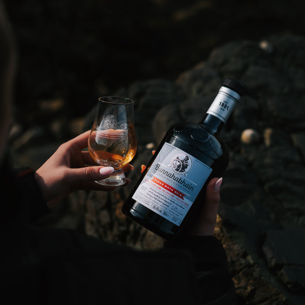 Someone holding Bunnahabhain Turas Math No.2 with a dram in opposite hand